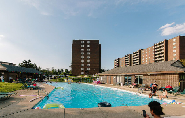 a large swimming pool with people in it and a building in the background