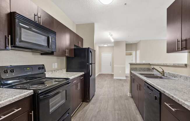 an empty kitchen with black appliances and granite counter tops