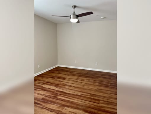 an empty living room with wood floors and a ceiling fan