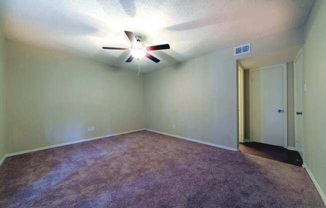 A room with a ceiling fan and carpeted floor.