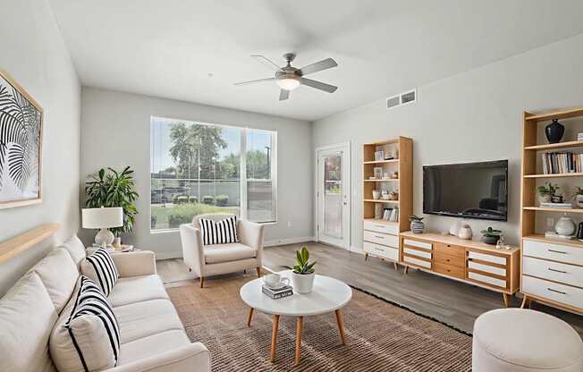 A living room with a white couch, a coffee table, and a television.