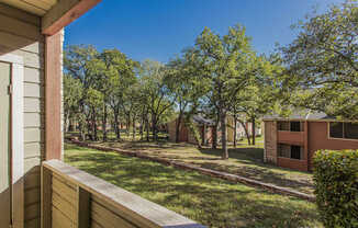 the view from the deck of a house with a yard and trees