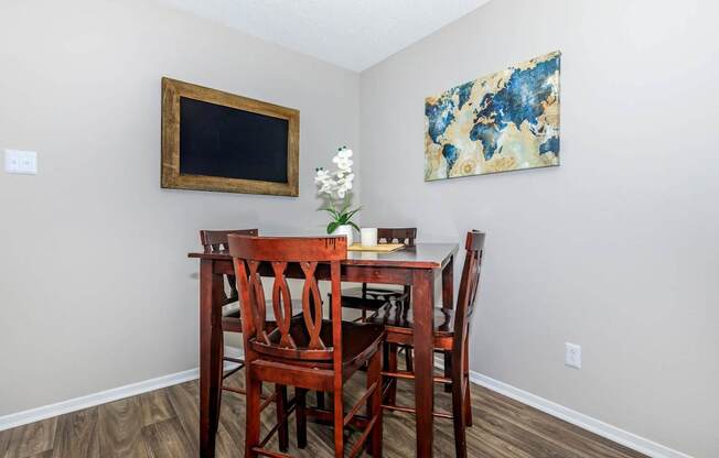 a dining room table with chairs and a painting on the wall at The Davis Apartments, Huntsville, AL 35816  