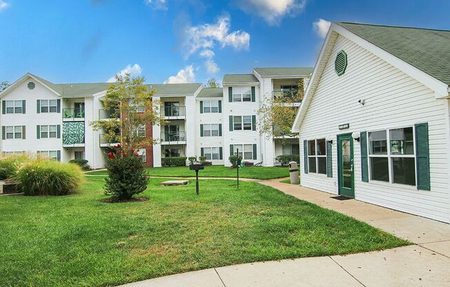 a sidewalk in front of an apartment building with green grass