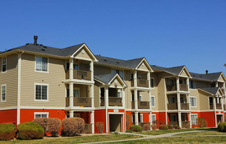 Ardenne Apartment Building with beigh and blue paint, green grass, and bright blue skies