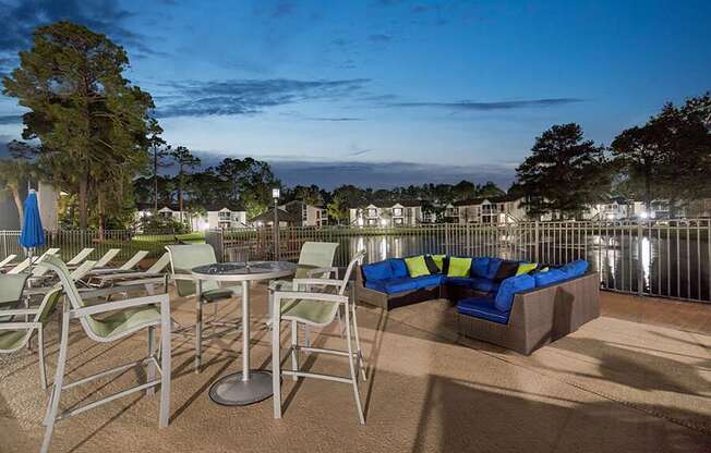 Outdoor BBQ Area with Lounge Furniture and View of Community Lake at Vue at Baymeadows Apartments located in Jacksonville, FL.