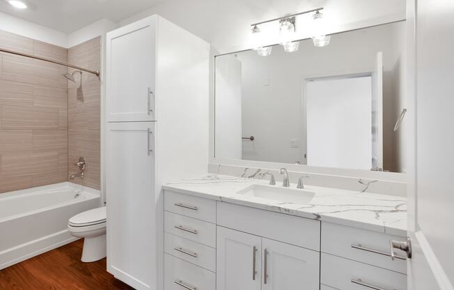 a bathroom with white cabinets and a white toilet and a sink