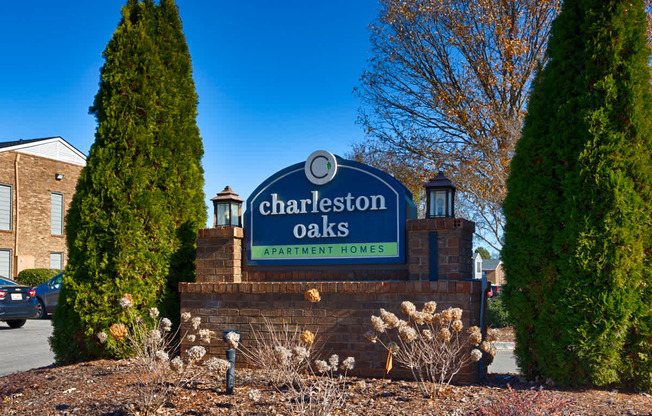 A sign for Charleston Oaks Apartment Homes is displayed in front of a building.