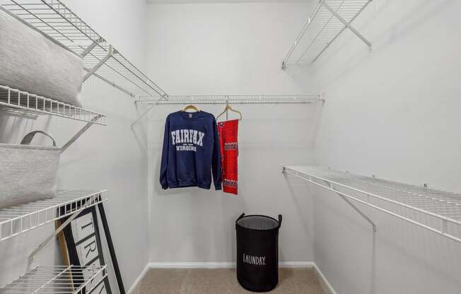 a walk in closet with white walls and white racks and a laundry room with clothes