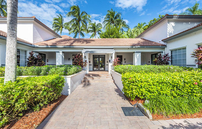 A white house with a red roof and a brick pathway leading to the front door.