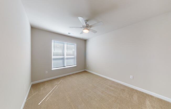 Bedroom with ceiling fan, carpet and door to bathroom