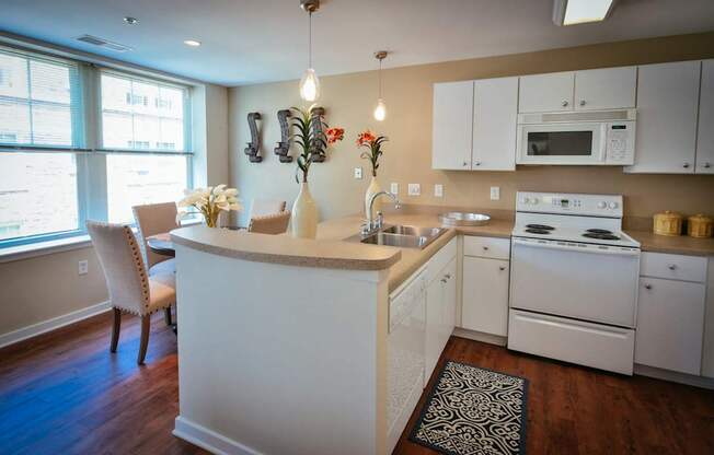 L-shaped kitchen with white cabinets and white range at Residences at Forest Park, Saint Louis, MO, 63108