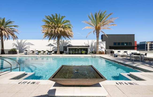 a swimming pool with palm trees and a building in the background