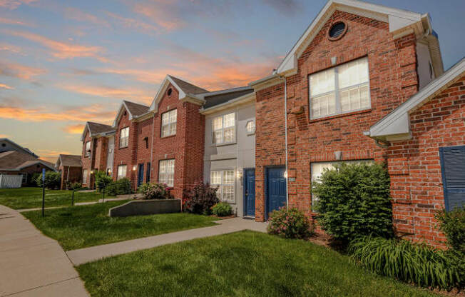 A row of red brick houses with green lawns in front.