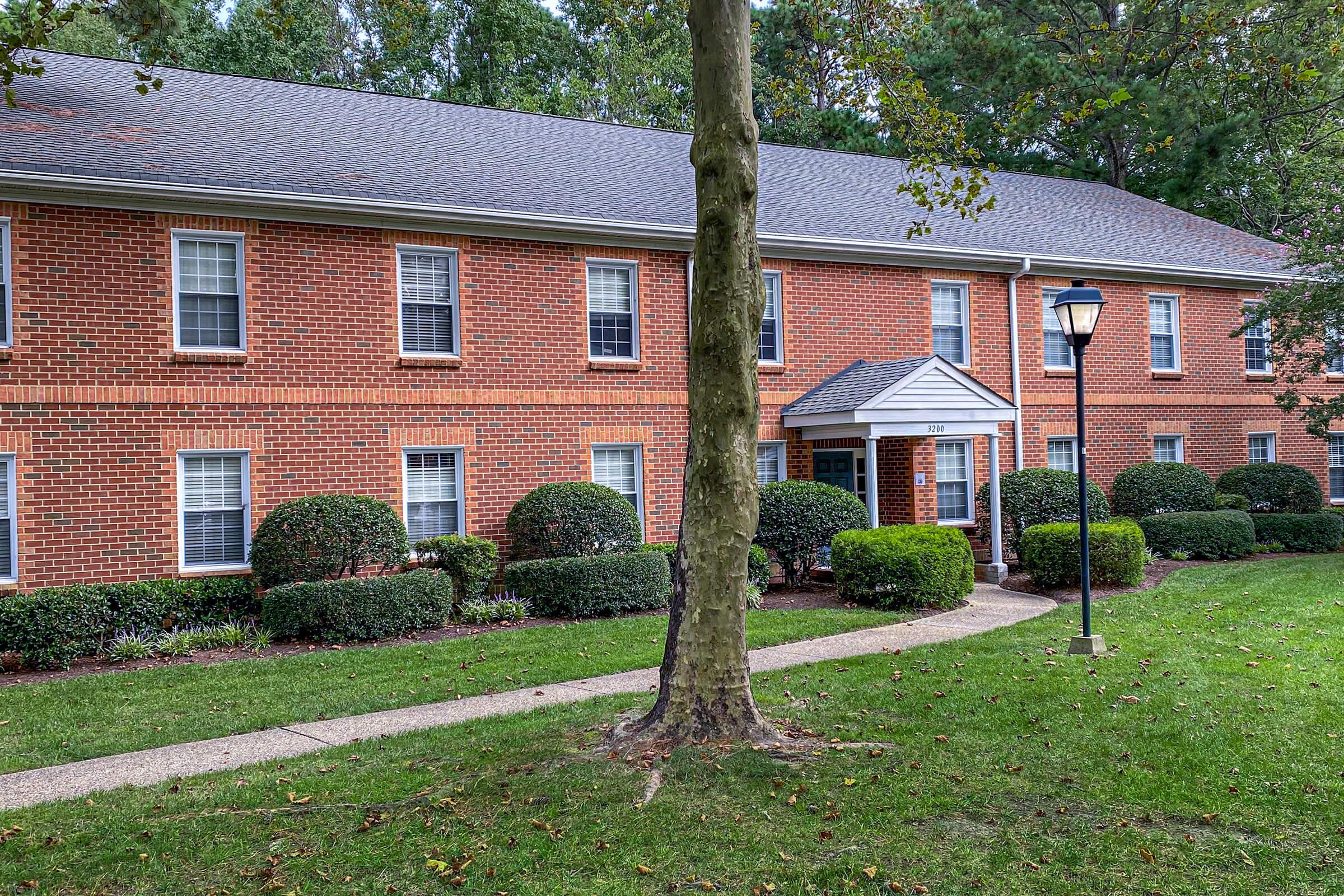 a large brick building with grass in front of a house