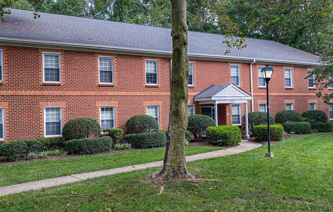 a large brick building with grass in front of a house