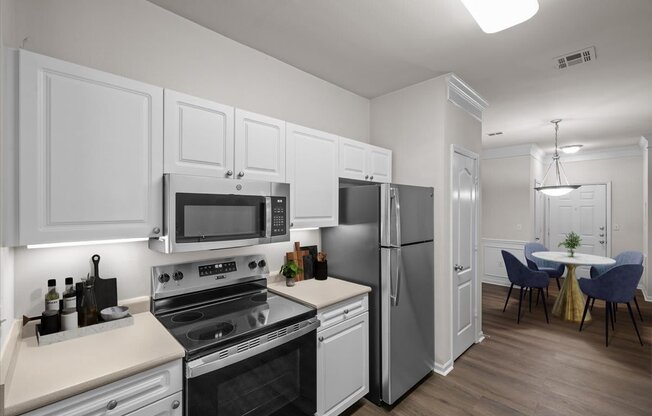 A modern kitchen with white cabinets and stainless steel appliances.