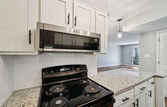 A black stove top oven with four burners is in a kitchen with white cabinets.