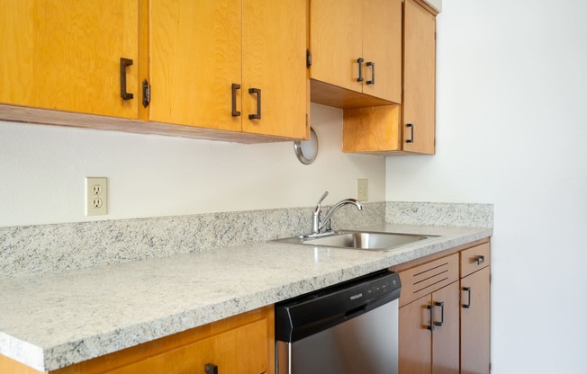 a kitchen with marble counter top and wooden cabinets