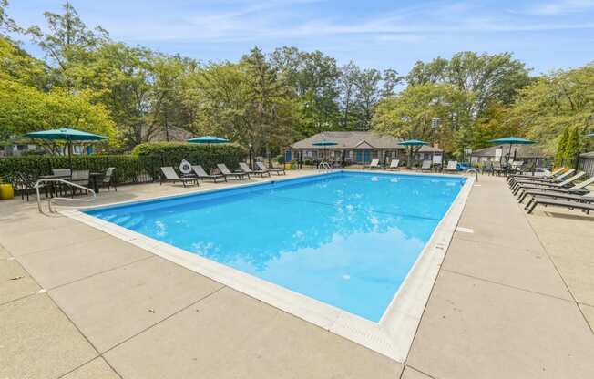 a swimming pool with chairs and umbrellas at the resort on a sunny day
