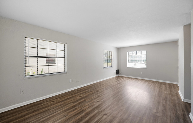 Spacious and bright living room with elegant wood flooring, large windows, and fresh neutral walls.