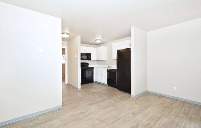 a renovated living room and kitchen with white walls and wood floors