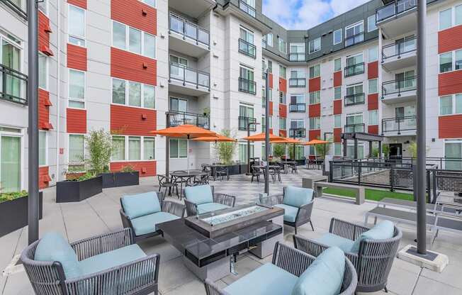 A patio with chairs and a table is surrounded by apartment buildings.