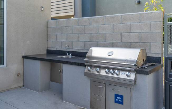 an outdoor kitchen with a grill and sink at Loma Villas Apartments, California, 92408