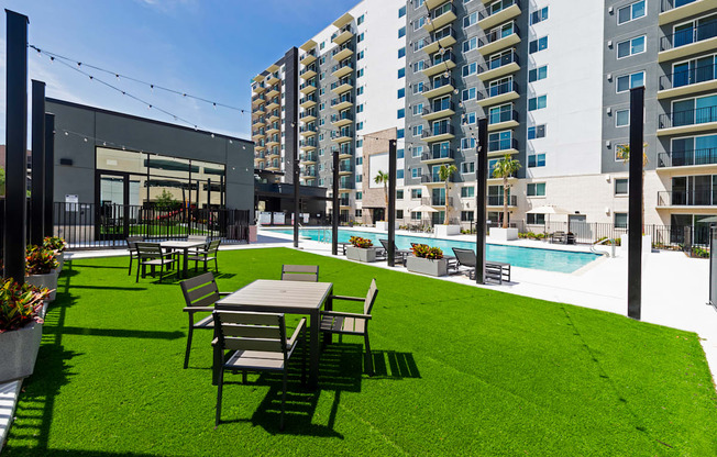 a large lawn with tables and chairs in front of an apartment building