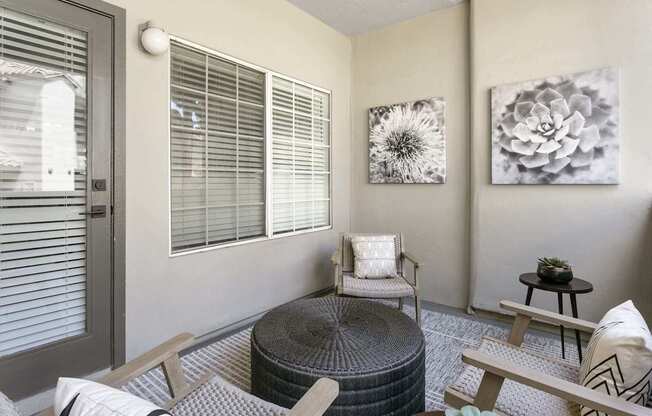 A living room with a grey ottoman, a grey chair, and a grey table.
