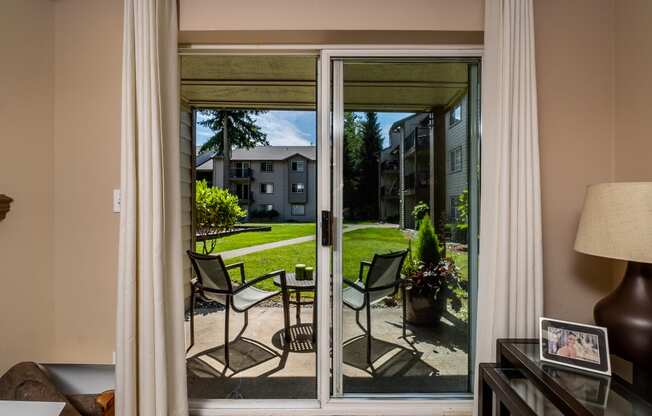 a patio with a table and chairs is seen through a sliding glass door