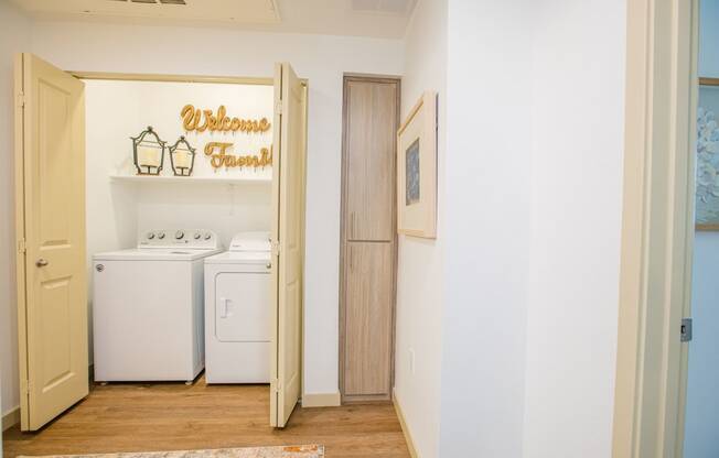 a laundry room with a washer and dryer and a sign on the wall