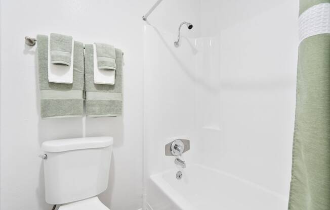 a bathroom with a shower and a toilet and towels