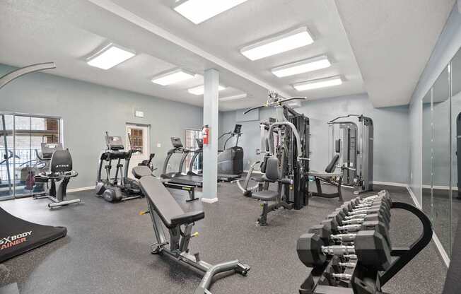 A gym with a variety of equipment including treadmills, weights, and exercise machines.