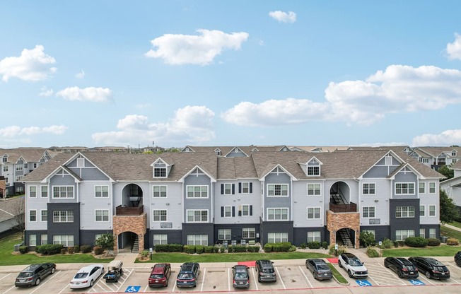 A large apartment complex with a parking lot in front.