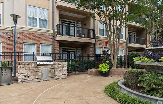 A brick building with a balcony and a small garden in front.