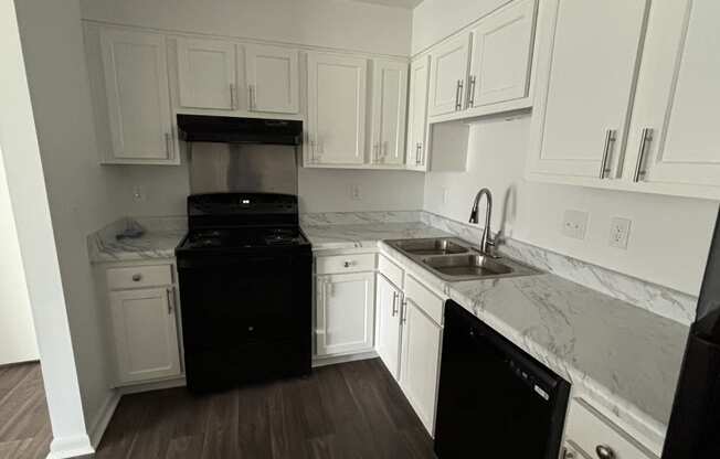 a kitchen with white cabinets and a black stove and a tv