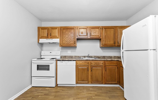 a kitchen with white appliances and wooden cabinets at Eagle Pointe New London, CT, 06320