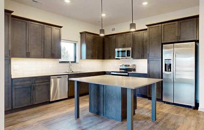 a modern L-shaped kitchen with dark cabinets, stainless steel appliances, quartz counter tops, and a central island table