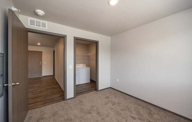 A white washing machine is in a small room with a brown carpet.
