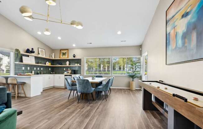 A well-lit room with a pool table and a dining table with chairs.