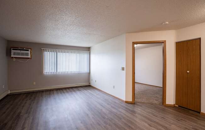 a living room with wood flooring and a door to a bedroom. Fargo, ND  Prairie Park Apartments