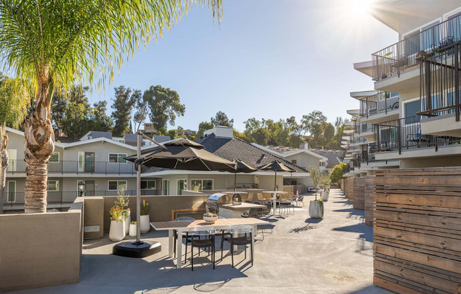 a patio area with tables and umbrellas at the enclave at university campuses