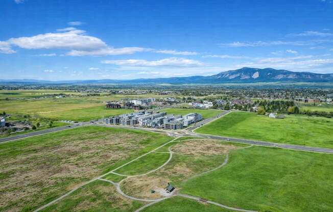 A large building complex is surrounded by a green field.