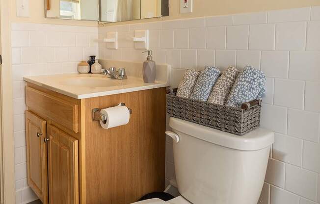 A white toilet with a wooden cabinet and a mirror above it.