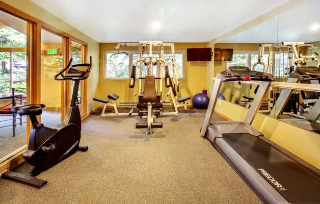 a gym with various exercise equipment in a room with windows