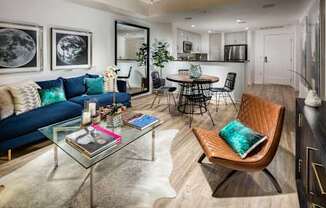 A modern living room with a blue sofa, a glass coffee table, and a brown leather chair.