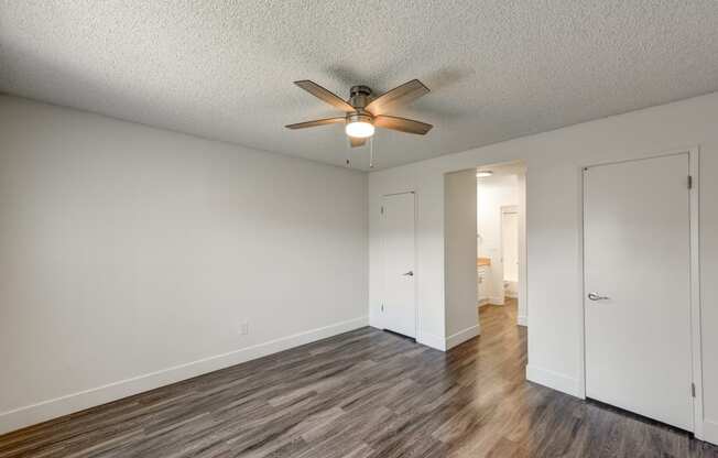 an empty living room with a ceiling fan and wood flooring