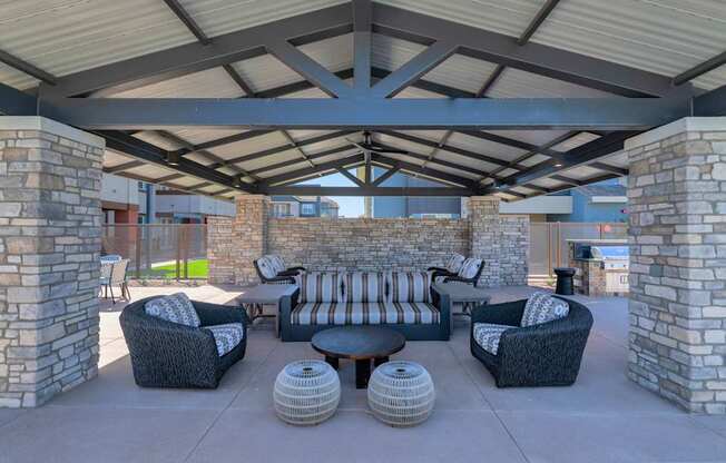 A patio with a stone pillar and a black couch.