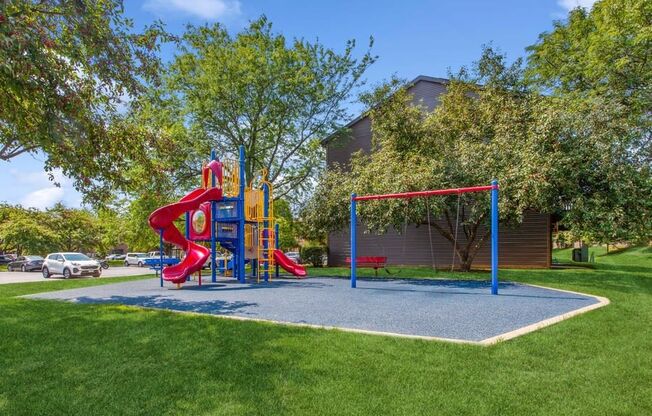 a playground with a slide and monkey bars in front of a building